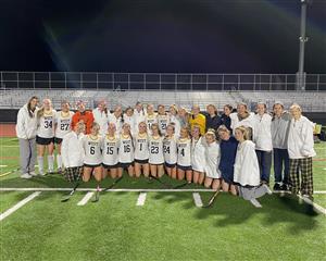 a field hockey team and their coaches pose for a photo